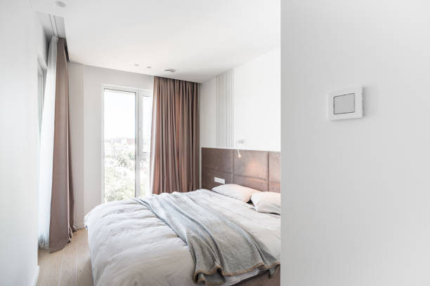 istock Cozy bedroom with large double bed and pinkish soft headboard and curtain 1280471255