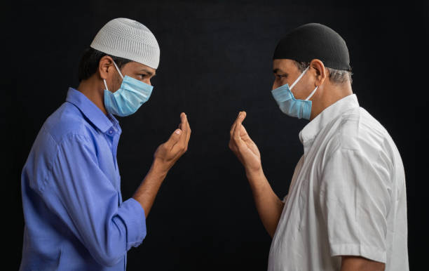 Two muslim men in medical mask greeting or salam each other in Islamic way while Maintaining social distancing - Concept of Coronavirus or covid-19 safety measures and new normal lifestyle. Two muslim men in medical mask greeting or salam each other in Islamic way while Maintaining social distancing - Concept of Coronavirus or covid-19 safety measures and new normal lifestyle father allah stock pictures, royalty-free photos & images