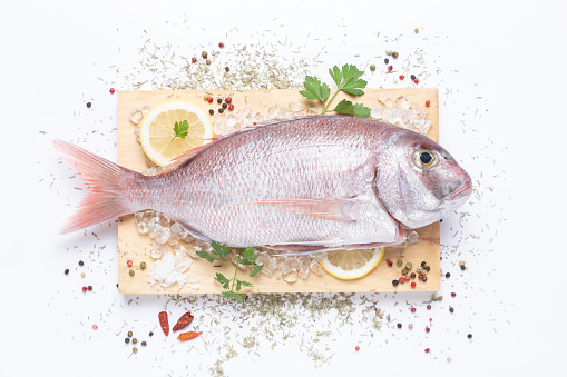 Fresh raw sea bream, with ingredients prepared for cooking, on  white background, top view.