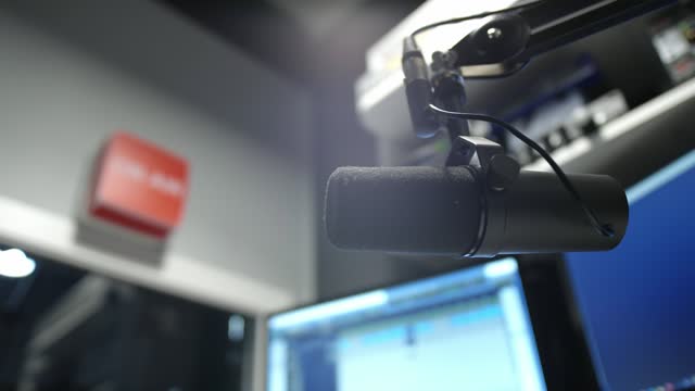 Microphone in a radio studio. DJ moves the microphone, starts broadcasting hot news. Records an evening podcast. Equipment in a recording studio