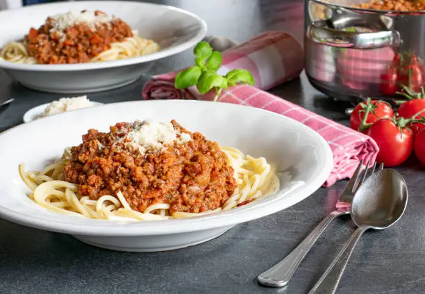homemade fresh bolognese sauce with Spaghettis served on a white pasta plate on a table - ready to eat