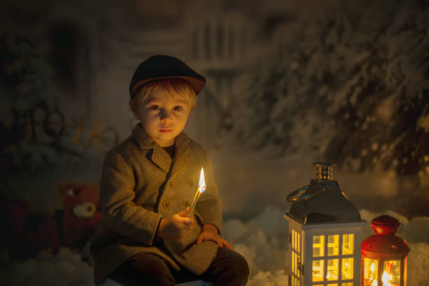 niño pequeño, mirando la llama de la lucha, sentado en la nieve - fairy child outdoors fairy tale fotografías e imágenes de stock