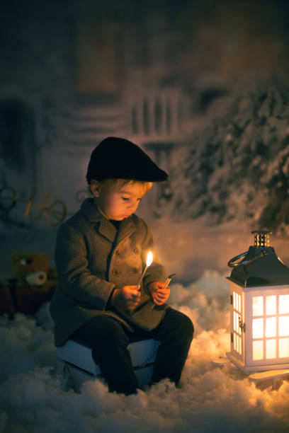 istock Little boy, looking at flame from match, sitting in the snow 1280478550