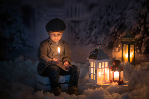 istock Little boy, looking at flame from match, sitting in the snow 1280478722