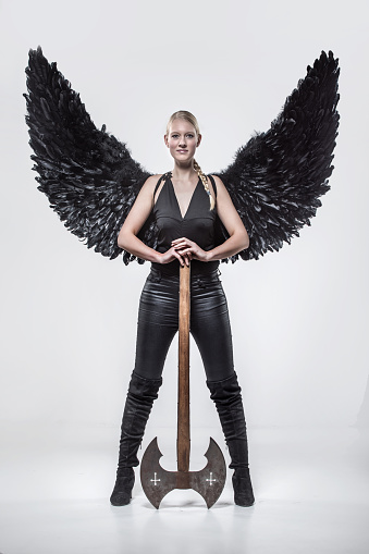 Blonde viking warrior female wearing black wings in studio shot