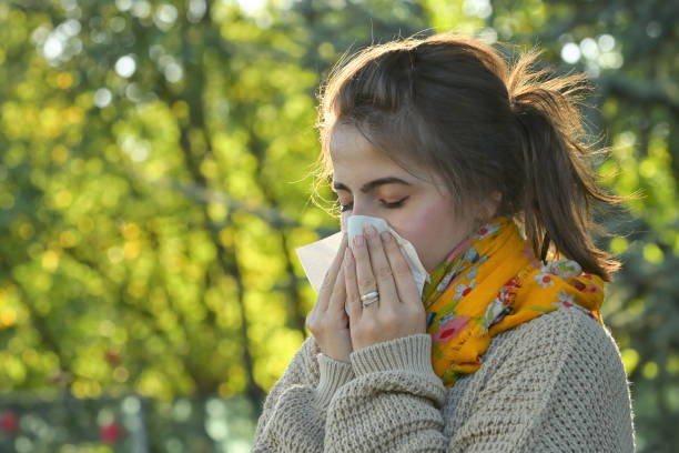 istock Girl in fall autumn park sneezing in tissue 1280483376