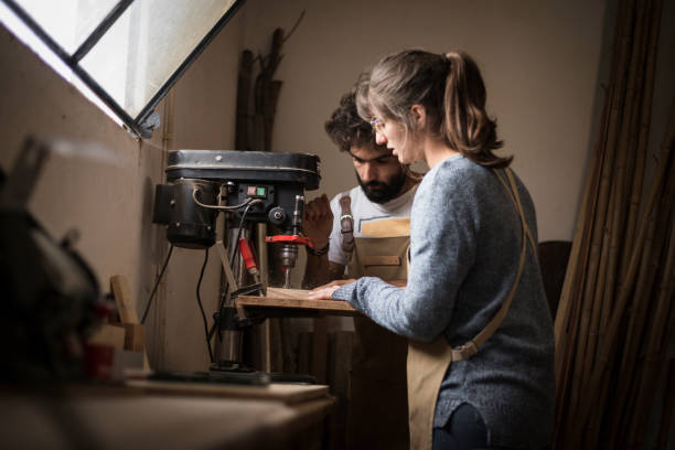 istock couple of carpenter working together in a small wood laboratory using a drill machine for timber. 1280491550