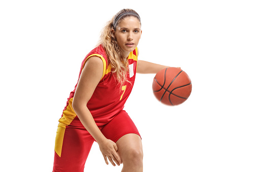 Portrait of young woman dribbling basketball during practice on court.