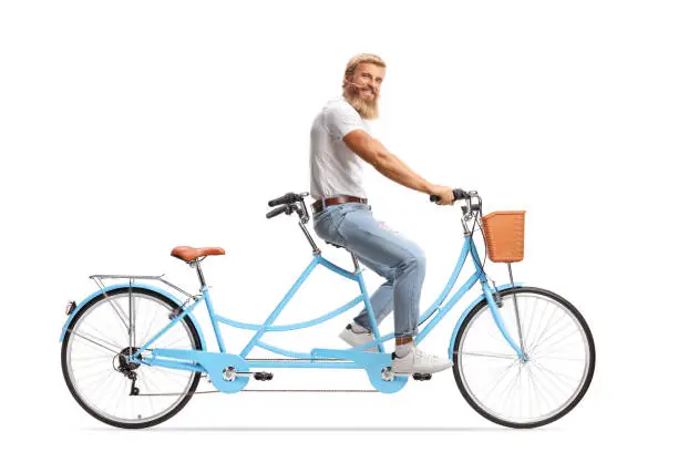 Photo of Young man with blond beard and moustachers riding a tandem bicycle