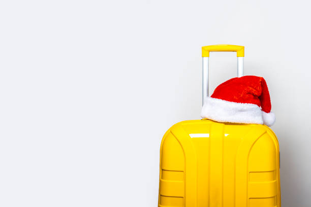 istock On a yellow plastic suitcase wearing a red Santa Claus hat on a light background 1280493336