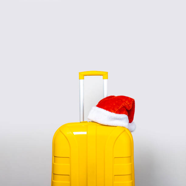 istock On a yellow plastic suitcase wearing a red Santa Claus hat on a light background 1280493533