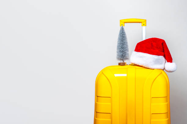 istock On a yellow plastic suitcase there is a small decorative Christmas tree and a red Santa Claus hat on a light background 1280494847