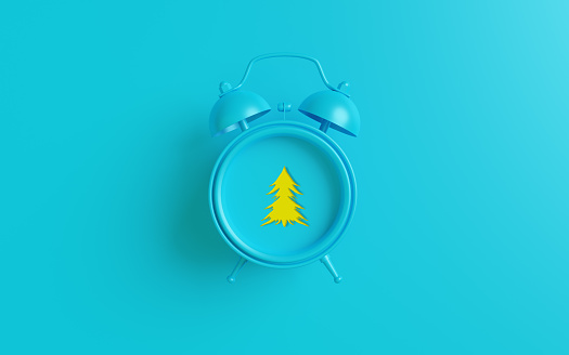 Blue alarm clock with Christmas tree symbol against blue background. Easy to crop for all your social media and print sizes with copy space.
