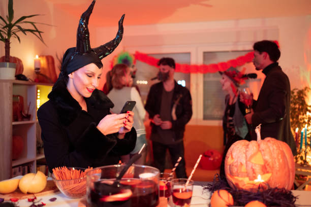 istock Young woman using her phone at the Halloween party 1280496644
