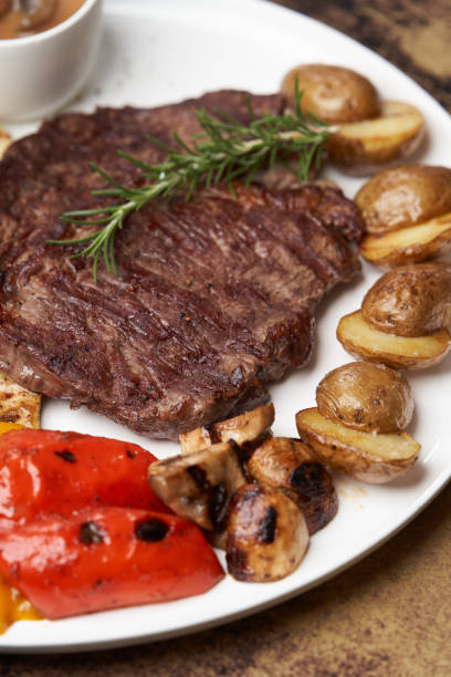 istock Ribeye steak with fried potatoes. Baked vegetables with beef steak on white plate 1280497070