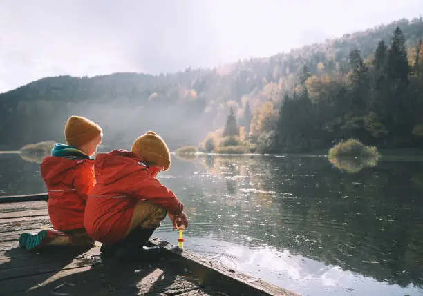 Photo of Children spend time outside in fresh and cold air. Small kids play in nature. Healthy childhood. Family life background.