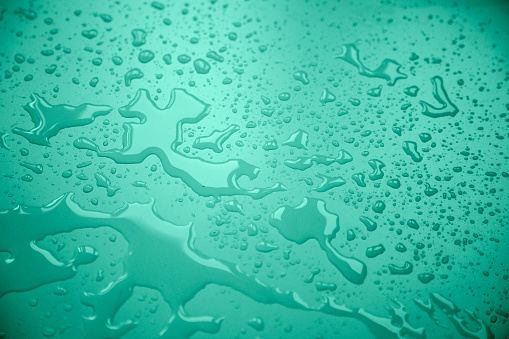 Green background with water drop or raindrops on the transparent window glass.