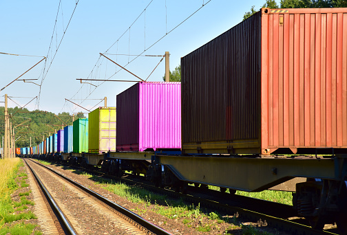 Cargo Containers Transportation On Freight Train By Railway. Intermodal Container On Train Car. Rail Freight Shipping Logistics Concept. Import - export goods from China.