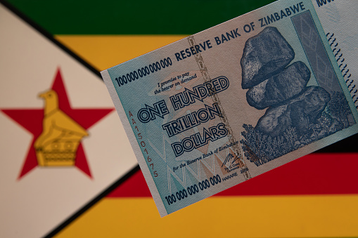 A unique one hundred trillion dollar banknote of the 2008 African State of Zimbabwe against the backdrop of the Zimbabwe flag