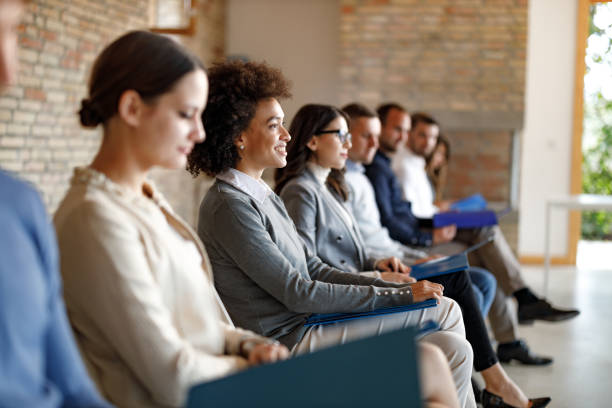 Group of candidate waiting for a job interview in the office. Large group of people sitting in waiting room before job interview for their potential business position. Focus is on happy black woman. hiring stock pictures, royalty-free photos & images