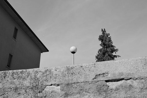 An isolated lamppost behind a reinforced concrete wall near a building (Gubbio, Umbria, Italy)