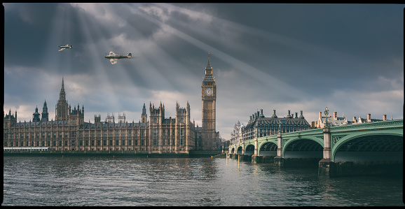 A classic Mk 1 Spitfire flies over the BritishParliament building. Model photography, composite image.