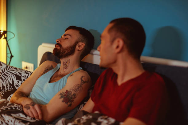 młody mężczyzna w łóżku ze swoim chłopakiem, czując się napadnięty i patrząc - gay man homosexual sex men zdjęcia i obrazy z banku zdjęć