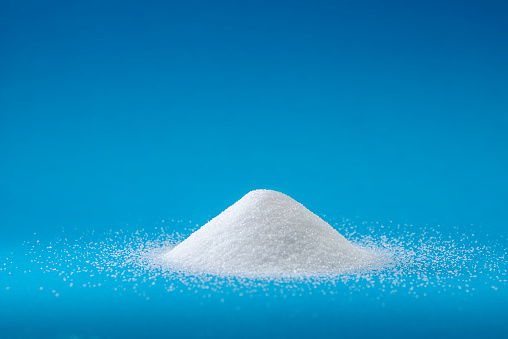 Heap of sugar with on blue background,