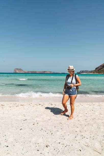 istock Woman travler with camera in her hands, walking down the sandy beach 1280511908
