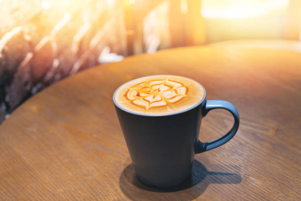 Cup of coffee with flower shaped froth on wooden table Cup of coffee with flower shaped froth on wooden table in Bangkok, Bangkok, Thailand cup shaped flower stock pictures, royalty-free photos & images