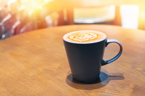 Cup of coffee with flower shaped froth on wooden table Cup of coffee with flower shaped froth on wooden table in Bangkok, Bangkok, Thailand cup shaped flower stock pictures, royalty-free photos & images