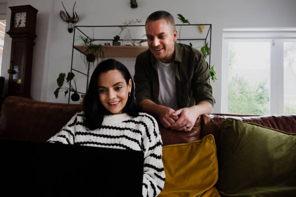 istock Happy couple online decor shopping using laptop sitting on sofa in lounge 1280513228