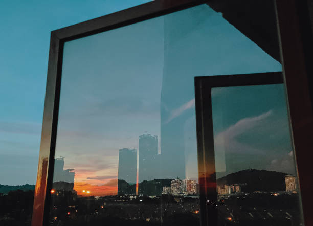 istock sunset looking through window at city with reflection on window with sunset sun 1280513526