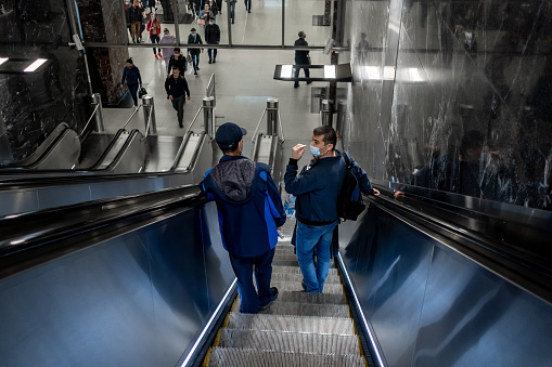 Moscow. Russia. October 5, 2020. Men wearing protective masks on their faces on a subway escalator descend into the underground. Compulsory wearing of masks in public places.