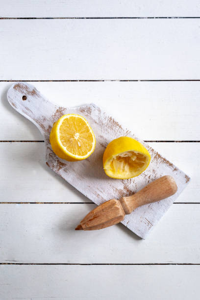istock Sliced lemon on a white cutting board with wooden juicer 1280514943