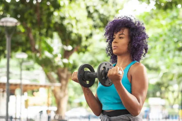 Photo of Young woman lifting dumbbell