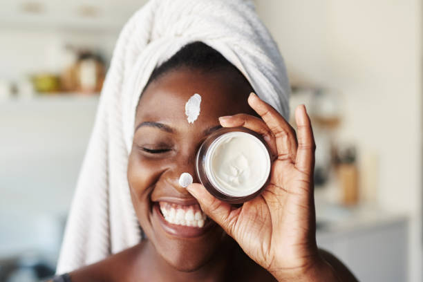 I love taking care of my skin Shot of a beautiful young woman holding up a face cream product grooming product photos stock pictures, royalty-free photos & images
