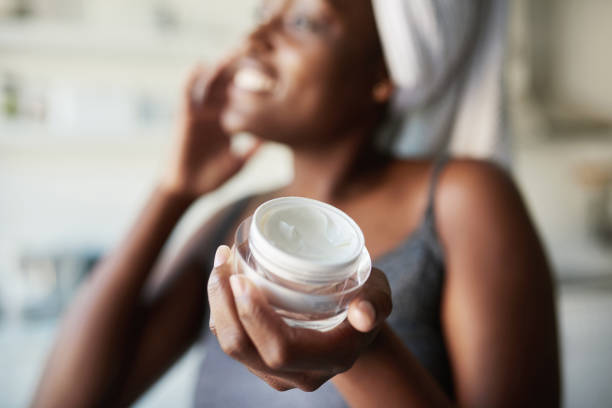 The secret to radiant looking skin Shot of a beautiful young woman holding up a face cream product face cream stock pictures, royalty-free photos & images