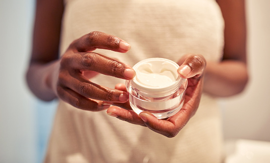 Cropped shot of a woman holding a skincare product in her hands