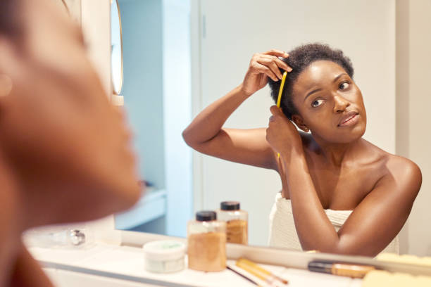 My 'fro is really growing Cropped shot of a young woman combing out her hair while looking in the bathroom mirror combing stock pictures, royalty-free photos & images