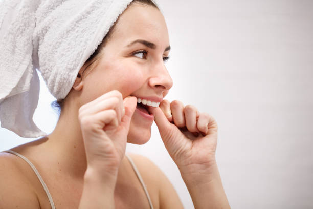 istock Three quarter front view of woman with towel on head flossing 1280518920