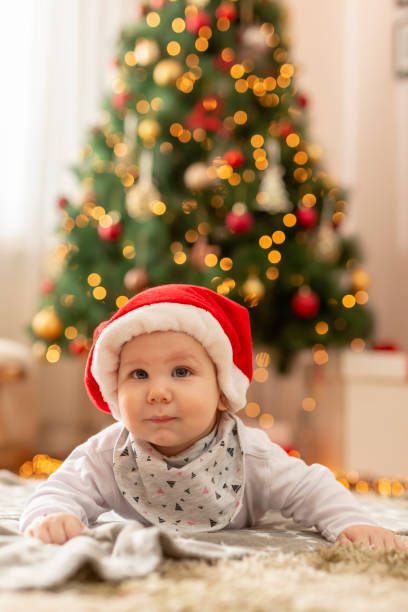 istock Baby boy wearing Santa hat lying next to Christmas tree 1280526126