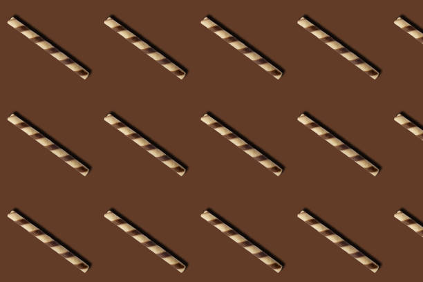 Pattern of chocolate and vanilla waffers on brown background.