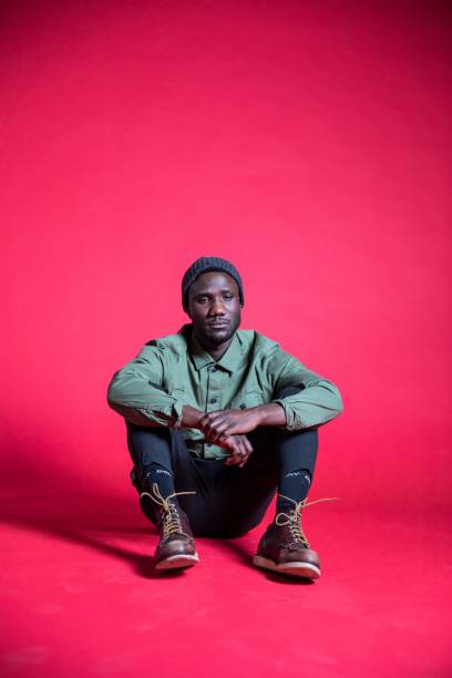 istock Young Black Man Sitting on Studio Floor with Sad Facial Expression 1280528128