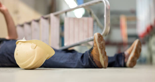 cuerpo masculino tirado en el suelo después de un accidente de trabajo. escalera caída y casco de seguridad situado junto al cuerpo. - falling ladder physical injury accident fotografías e imágenes de stock