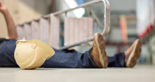 男性の体は、労働災害の後、床に横たわっている。体の隣に横たわっている倒れたはしごと安全ヘルメット。 - body construction ストックフォトと画像