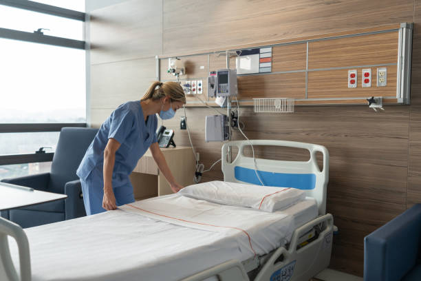 istock Nurse wearing a facemask while making the bed at a hospital room 1280532509