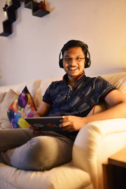 istock Teenage boy using digital tablet sitting on sofa in living room 1280532584