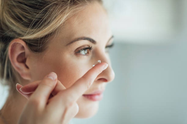 Putting in A Contact Lens A side view, close-up shot of a beautiful blonde woman putting in a contact lens. contact lens stock pictures, royalty-free photos & images