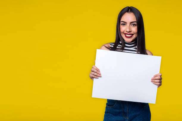 istock Woman holding white sign, isolated on yellow background with space for text 1280540794